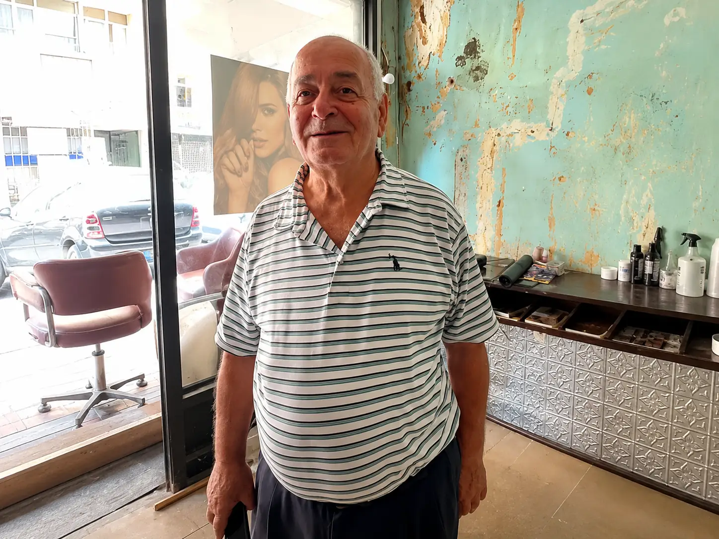 Elias Abboud standing inside his hair salon on Pierre Gemayel Street in Aïn el-Remmaneh, Lebanon